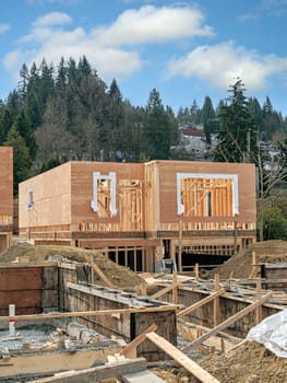 Wooden frame of new house with concrete filled fundation prepared for another house in front