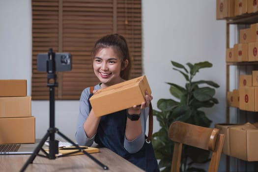Asian blogger review products and video camera on her phone, sell them online, and showcase her products online on social media. ecommerce business live streaming vlog new normal concept.