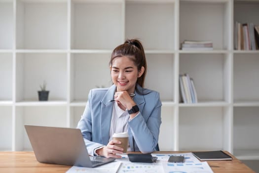 Asian businesswoman use laptop computer in office The Internal Revenue Service audit document balance calculation report is being prepared..