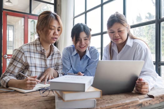 Asian College groups of students using laptop, tablet, studying together with notebooks documents paper for report near windows in classroom. Happy young study for school assignment