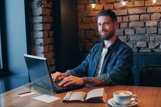 No minute without my laptop. Handsome young man working on laptop while enjoying coffee in cafe.