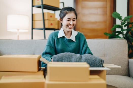 Starting small business entrepreneur of independent Asian female online seller packing products to send to customers and SME delivery concept.