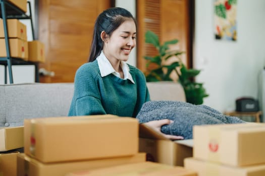 Starting small business entrepreneur of independent Asian female online seller packing products to send to customers and SME delivery concept.