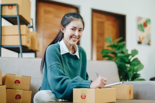 Starting small business entrepreneur of independent Asian female online seller packing products to send to customers and SME delivery concept.