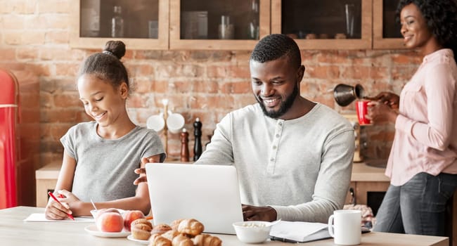Happy afro family having breakfast together in kitchen, dad surfing internet on laptop, making plans for weekend, copy space