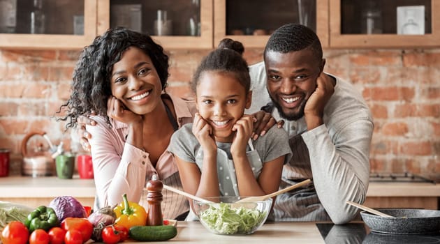 Adorable afro family cooking healthy dinner together at kitchen, posing at camera, making salad, copy space