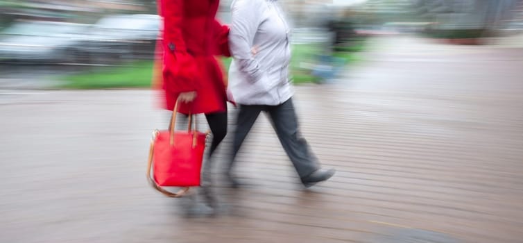 Two women on the street hurrying about their business. City life in a motion blurred style. 
