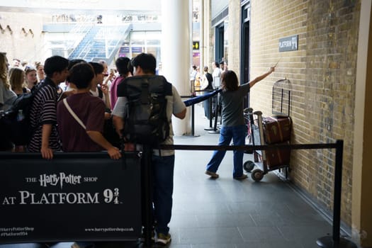 LONDON, UK - SEPTEMBER 6, 2023: People waiting in queue for photograph with Harry Potter's trolley at the imaginary Platform 9 34 at Kings Cross Station in London, England, UK