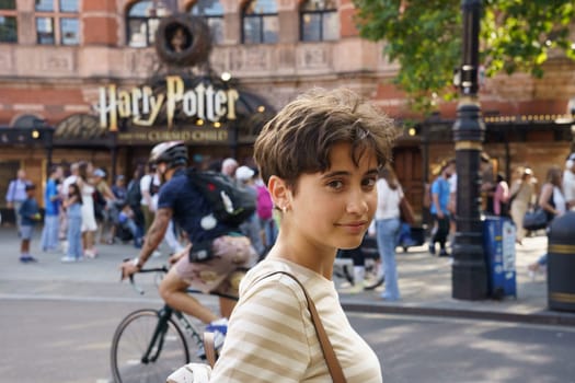 London, United Kingdom, july 18th 2024. Teenage girl in front of the facade of The Palace theatre in London. Play with the musical play Harry Potter and the Cursed Child.