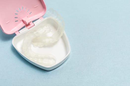 Dirty Teeth Dental Night Guards in Box, White Pink Container. Blue Background. Copy Space For Text. Clear Retainer. Oral Hygiene, Cleaner. Horizontal Plane. High quality photo