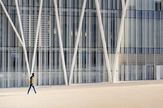 young black man walking in front of a modern office building, lifestyle concept