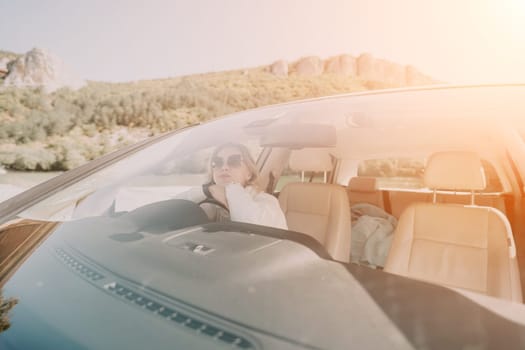 A person drives a car with the sun shining brightly through the windshield.