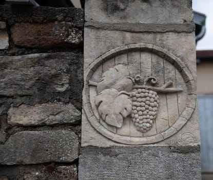 engraving of a bunch of grapes with vine and leaves on a wall
