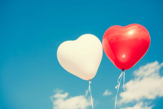 Heart-shaped red and white balloons floating in the sky with clouds, symbolizing love and romance
