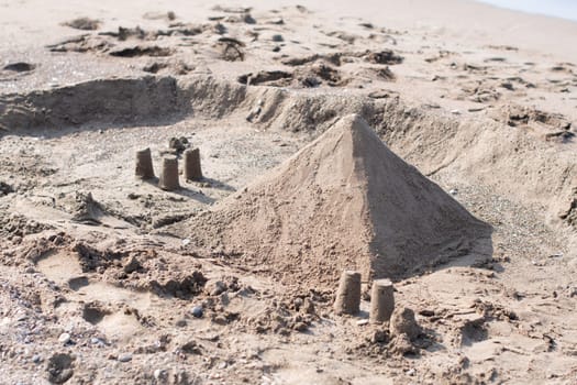 Sand pyramid on the beach with the sea in the background, summer vacation in a tropical country