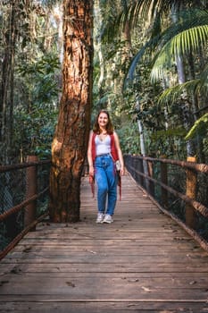 Brazilian woman with a red sweater, Standing on a wooden bridge at a hiking trail. Jardim Botanic Garden, São Paulo, Brazil.