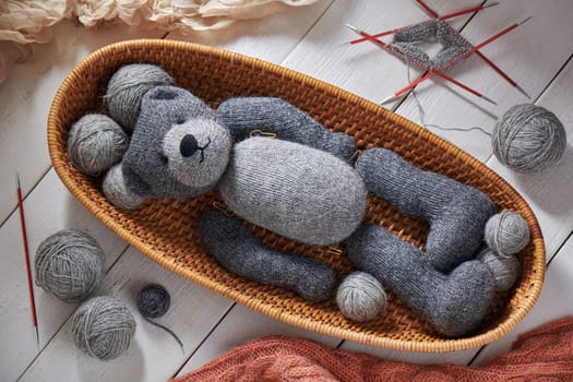 Knitted details of a toy teddy bear lying in a wicker basket