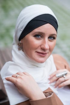 Portrait of a young blue-eyed woman in a hijab outdoors