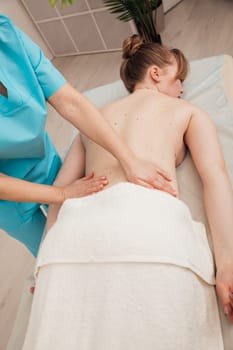 a massage therapist massages the back of a woman on the couch in the office relaxation relax osteopathy