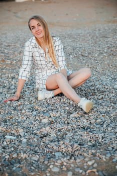 beautiful woman sitting on pebbles on the shore