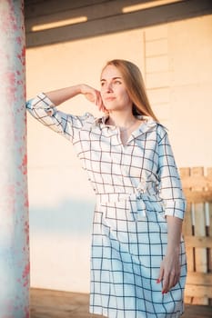 a woman in a plaid dress stands at a pole