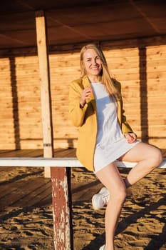 blonde girl in a yellow jacket sitting on a wooden building