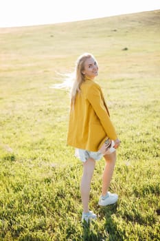 a beautiful blonde in a yellow jacket in nature green glade