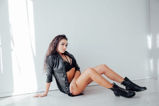 a brunette in black underwear and clothes sits on the floor in the room