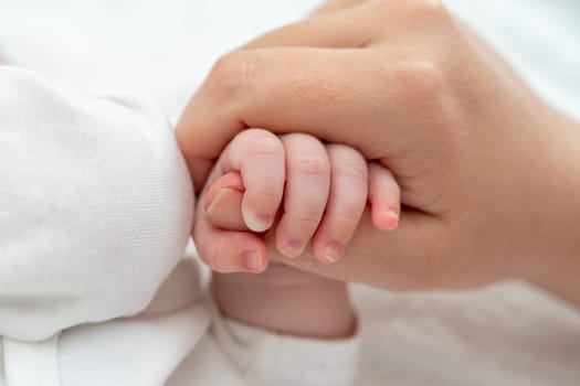 Close-up captures a newborn baby tenderly holding onto the mother's thumb, showcasing innate bond and trust