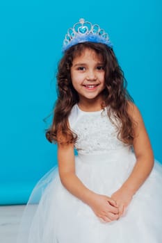 girl in a white dress with a crown on her head for a holiday on a blue background