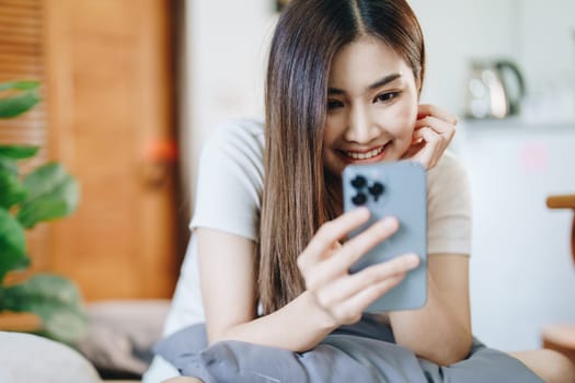 Happy girl checking social media holding smartphone sitting at sofa in living room at home. relaxing concepts