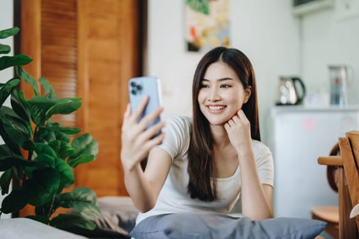 Happy girl checking social media holding smartphone sitting at sofa in living room at home. relaxing concepts