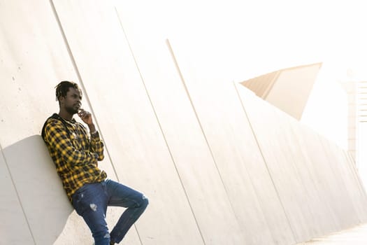 young black man leaning against a modern concrete structure at sunset, lifestyle concept