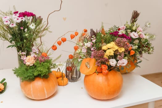Flower arrangement in a pumpkin, autumn interior decor. Creating handmade autumn decor