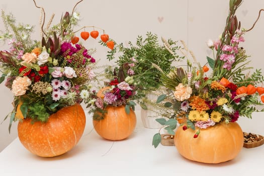 Flower arrangement in a pumpkin, autumn interior decor. Creating handmade autumn decor