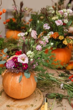 Flower arrangement in a pumpkin, autumn interior decor. Creating handmade autumn decor