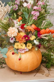 Flower arrangement in a pumpkin, autumn interior decor. Creating handmade autumn decor