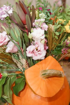 Flower arrangement in a pumpkin, autumn interior decor. Creating handmade autumn decor