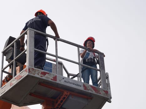 Varna, Bulgaria - September, 13, 2020: fireman and girl in safety helmets in a basket of a retractable fire boom, bottom view