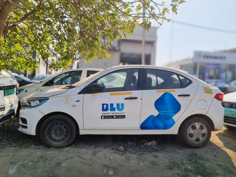 Delhi, India - 9th Mar 2024: Electric EV cars from popular ride haling online app Blusmart Blu standing in tree shade