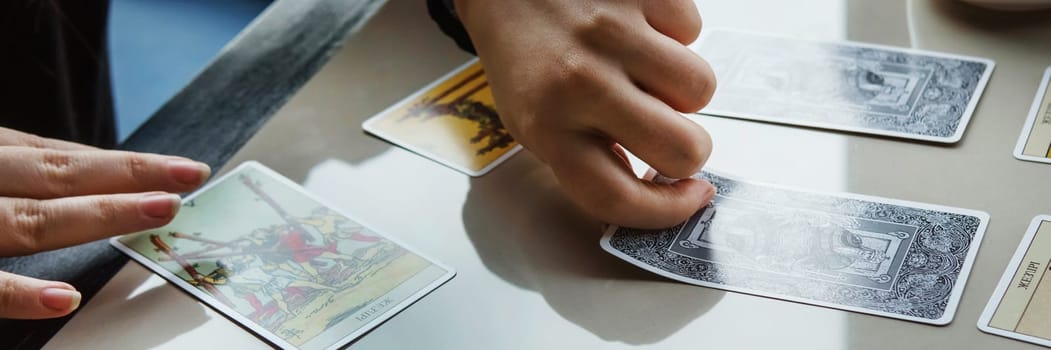 TVER, RUSSIA - FEBRUARY 11, 2023. Tarot cards, Tarot card divination, esoteric background. A woman makes a layout on the cards at the table. Divination, predictions on tarot cards