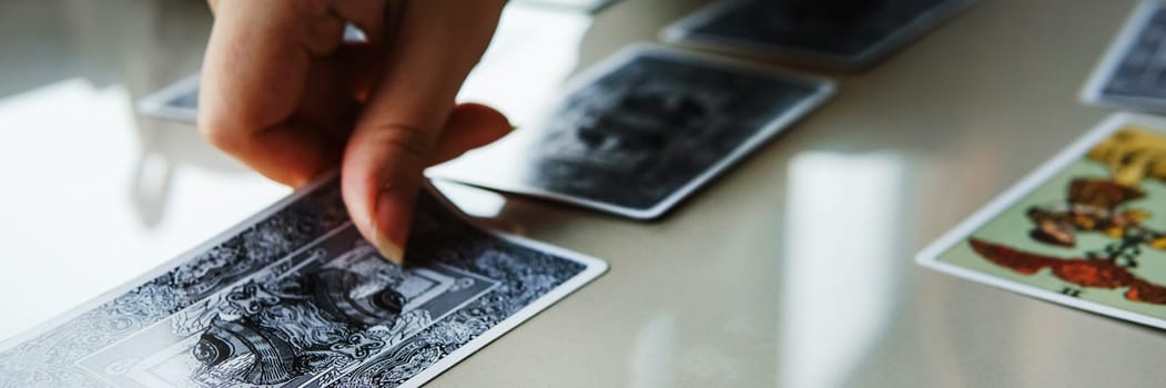 TVER, RUSSIA - FEBRUARY 11, 2023. Tarot cards, Tarot card divination, esoteric background. A woman makes a layout on the cards at the table. Divination, predictions on tarot cards