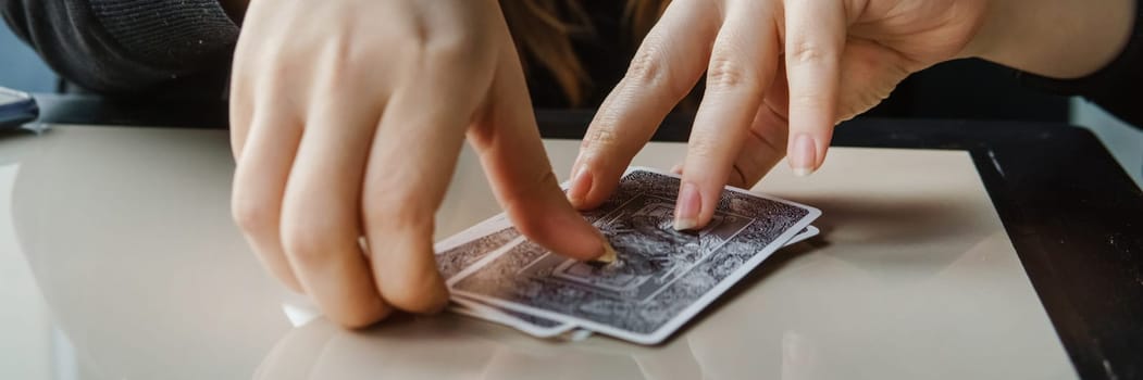TVER, RUSSIA - FEBRUARY 11, 2023. Tarot cards, Tarot card divination, esoteric background. A woman makes a layout on the cards at the table. Divination, predictions on tarot cards