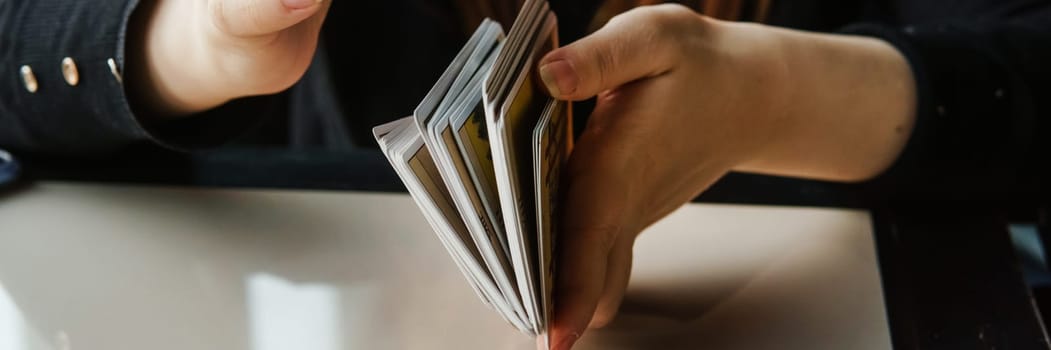 TVER, RUSSIA - FEBRUARY 11, 2023. Tarot cards, Tarot card divination, esoteric background. A woman makes a layout on the cards at the table. Divination, predictions on tarot cards