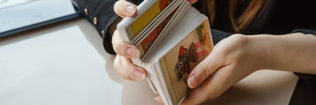 TVER, RUSSIA - FEBRUARY 11, 2023. Tarot cards, Tarot card divination, esoteric background. A woman makes a layout on the cards at the table. Divination, predictions on tarot cards