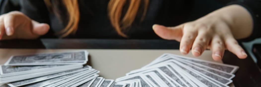 TVER, RUSSIA - FEBRUARY 11, 2023. Tarot cards, Tarot card divination, esoteric background. A woman makes a layout on the cards at the table. Divination, predictions on tarot cards