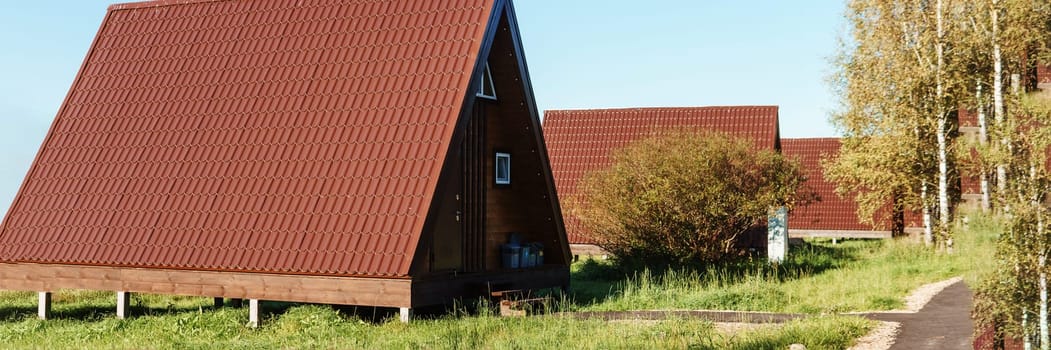 The concept of glamping and renting a chalet for weekend. Wooden house with a veranda in nature around coniferous trees.