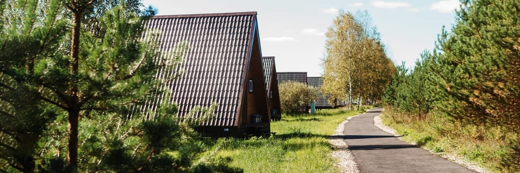 The concept of glamping and renting a chalet for weekend. Wooden house with a veranda in nature around coniferous trees.