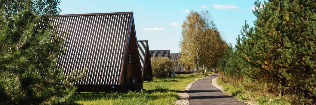 The concept of glamping and renting a chalet for weekend. Wooden house with a veranda in nature around coniferous trees.