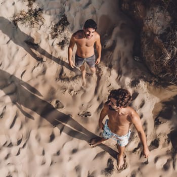 Two friends enjoying a sunny day at the beach, laughing and having fun on the sandy shore.